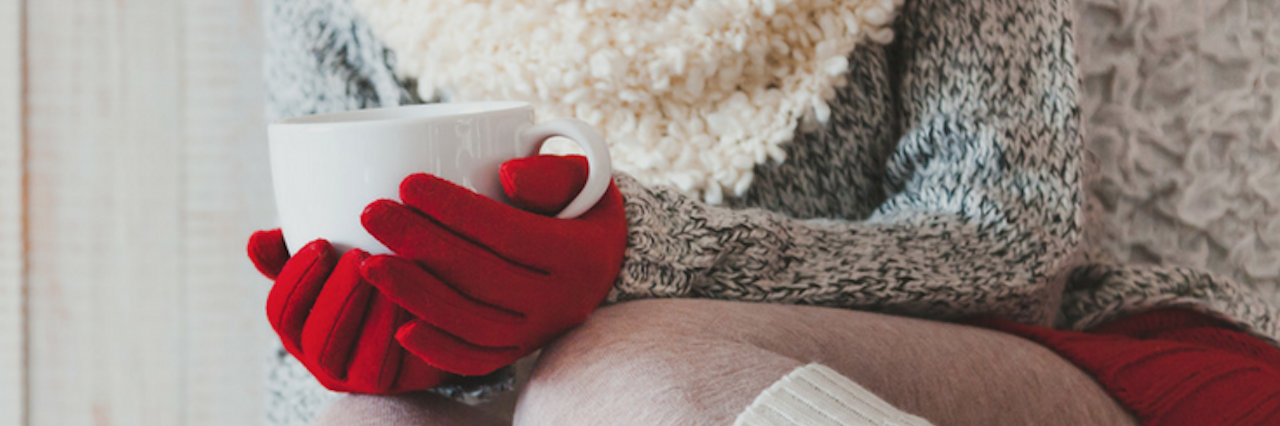 woman curled up on the couch holding a mug of tea with the words 'christmas with a chronic illness'
