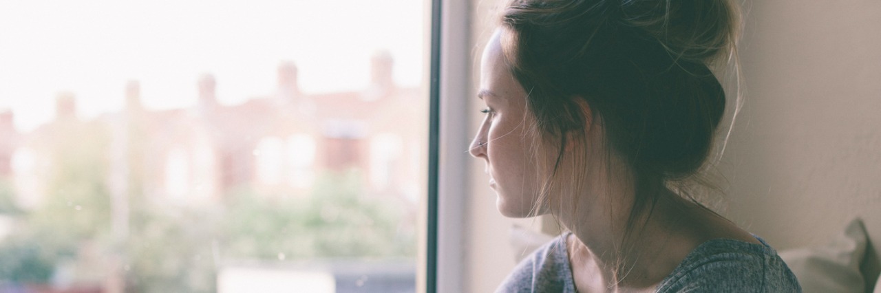 Crohn's and Colitis Awareness Awareness Week: What I Want You to Know Blonde girl with hair tied up sits with her knees up looking though a large window
