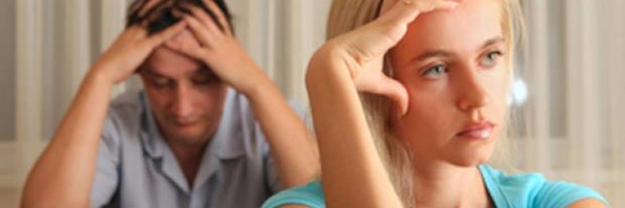 Becoming Resentful and Frustrated When Helping Sick Friends woman leans against her hand looking angry and a man sits behind her with his hand in his hands