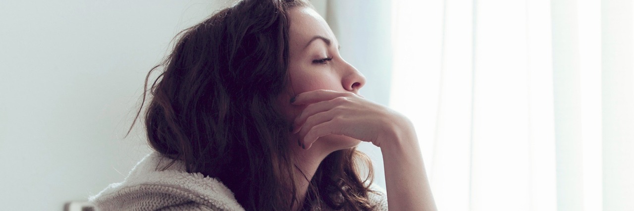 woman sitting on bed thinking and looking out window