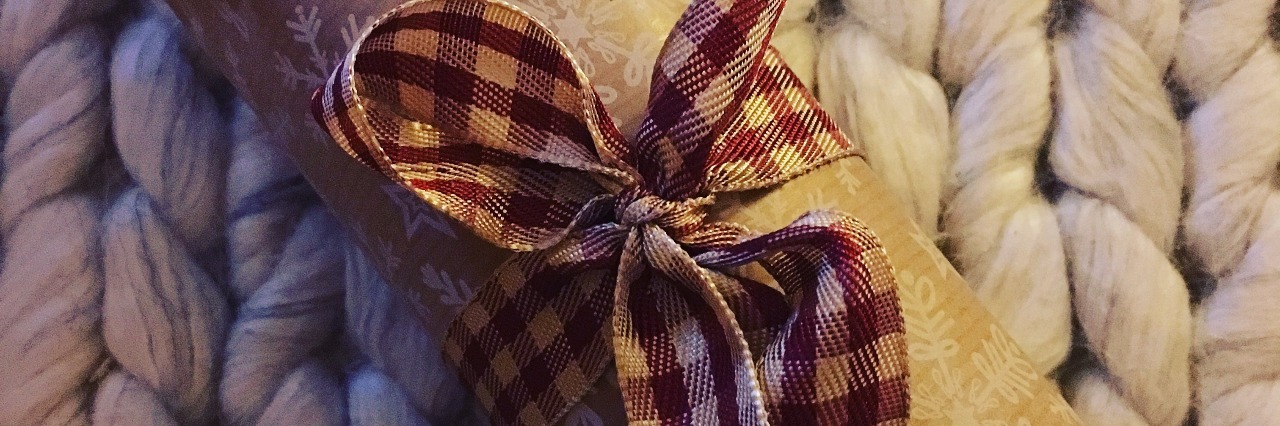 cylinder shaped gift wrapped in paper and tied with fabric bow