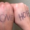 Two hands with the words "love" and "hope" written on them