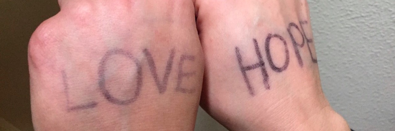 Why I Felt Alienated at the Women's March as a Woman With Bipolar Two hands with the words "love" and "hope" written on them
