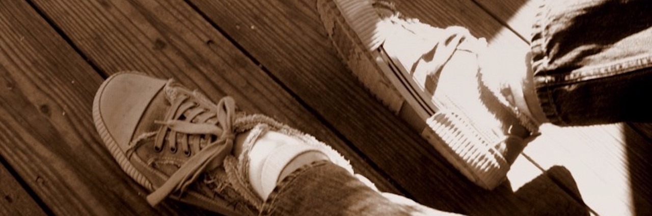 Lyme Disease: Learning to Be Kinder and More Understanding a person's feet wearing old sneakers against a wooden floor with sunlight hitting the feet