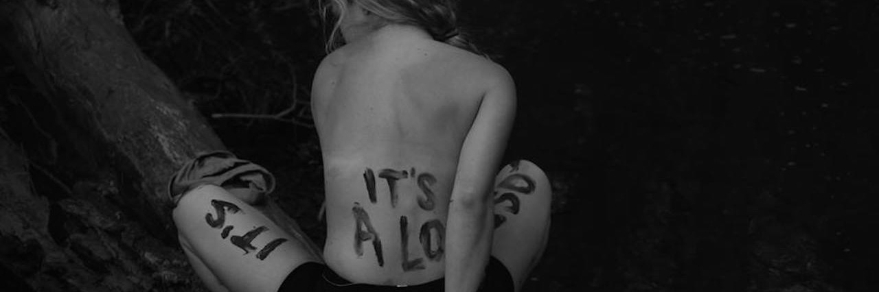 A woman sitting on a tree, back facing the camera