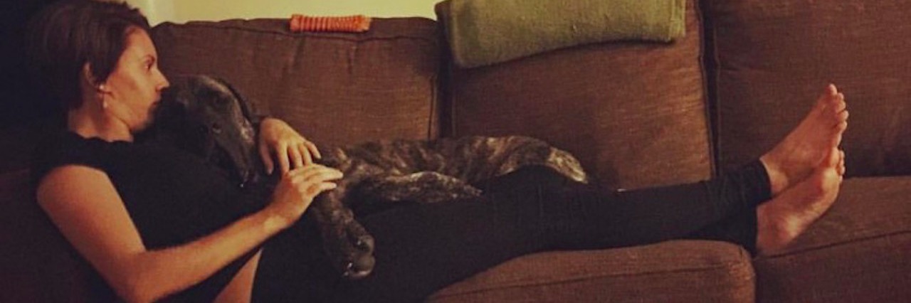 woman laying on a couch with her english mastiff