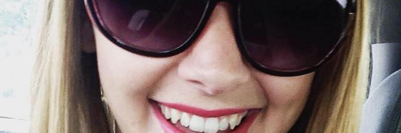 Acting and Pretending to Be Healthy With Chronic Illness selfie of a blond woman in the car wearing sunglasses and red lipstick