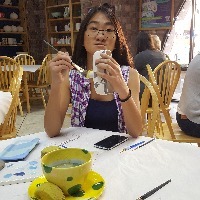 girl sitting at table painting pottery