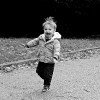 black and white photo of little boy running down road