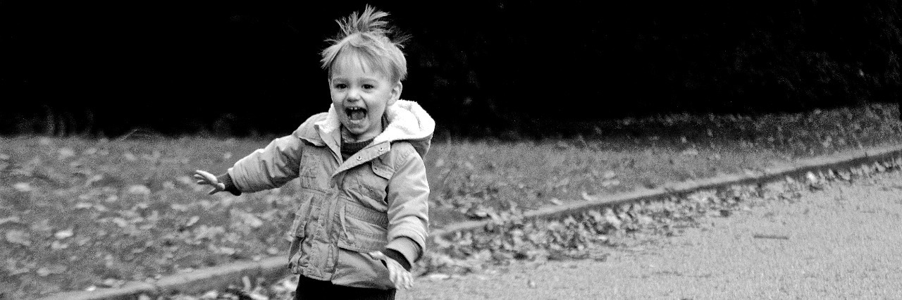 black and white photo of little boy running down road