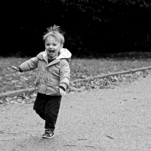 black and white photo of little boy running down road