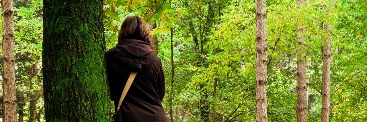 Experiencing a Migraine and Depression at the Same Time woman leaning against a tree