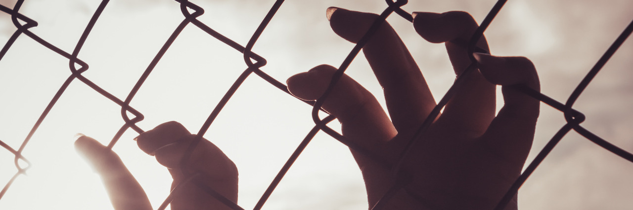How Depression Makes Your Body Feel Female hand holding on chain link fence