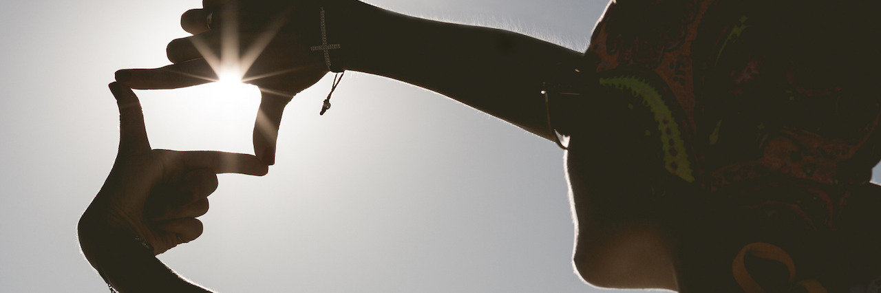 5 Positive Things About Living With Mental Illness Woman frames the sunset with her hands