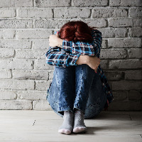 Depressed young crying woman leaning on her knees