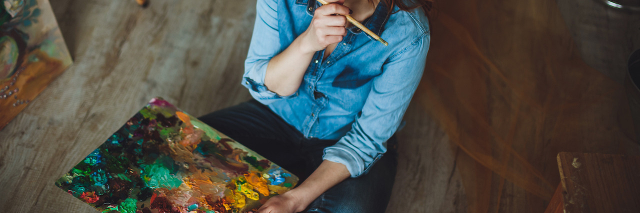 How to Defy the Picture Society Paints of Mental Illness Female artist sitting with her brush and painting