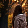 Woman alone in autumn park in front of sunset
