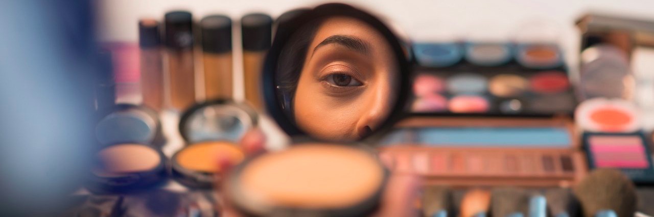 Tricuspid Atresia: I Wear Makeup to Feel Healthy, Not Pretty woman looking in compact mirror before putting on makeup