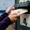 A woman's hands placing a letter in a mailbox