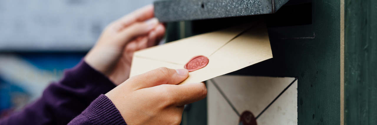 A woman's hands placing a letter in a mailbox