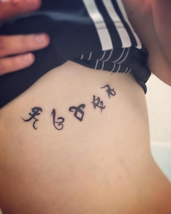A tattoo of small symbols on a woman's upper torso.