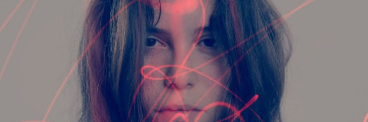Through the Lens of the Photographer With Bipolar Disorder A double exposure image of a woman's face and red lights shining on her