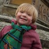Rory, a little boy with Down syndrome who is wearing a maroon winter coat and green striped scarf.