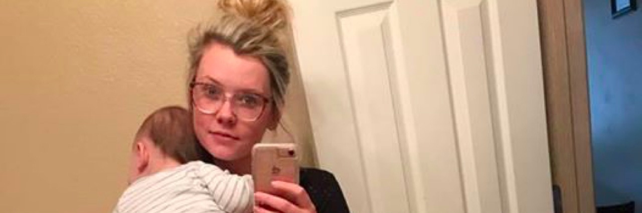 Cierra Lyn Fortner taking a mirror selfie in the bathroom while holding her son.
