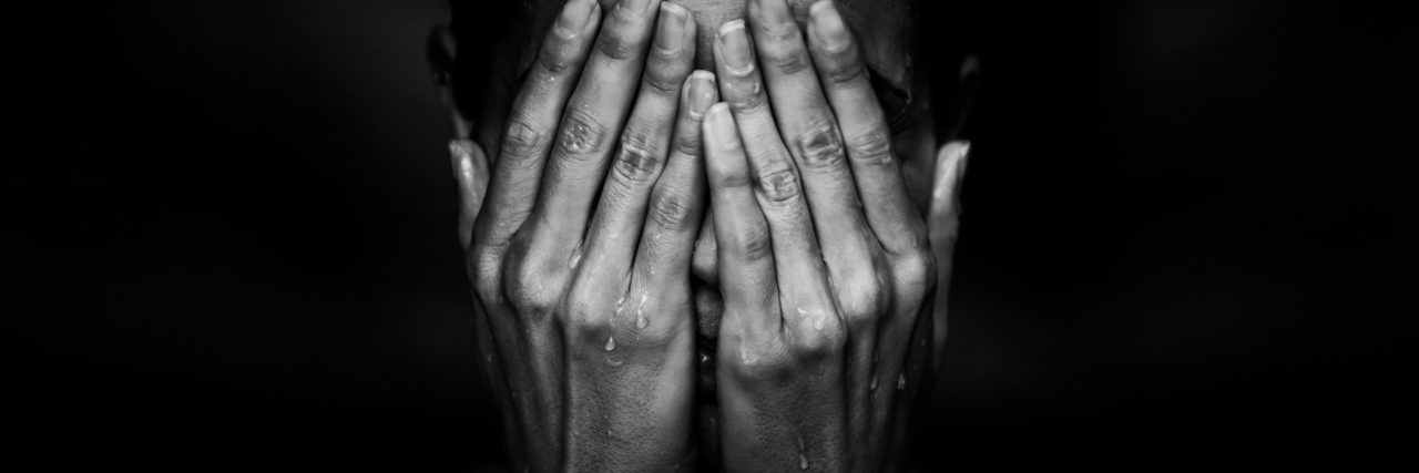 New Year's Resolutions to Try If You Are Grieving Tears through hands of woman's face