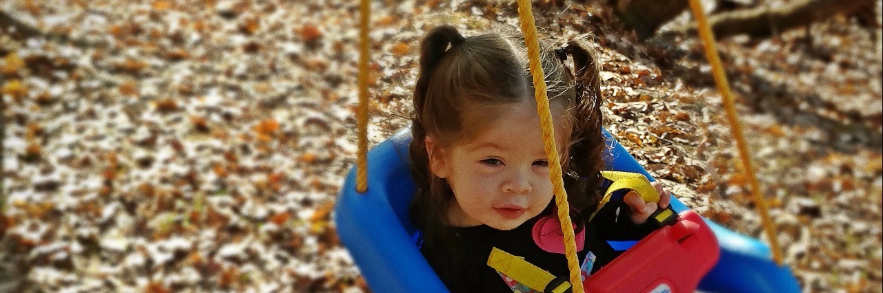 little girl with cantu syndrome in a swing