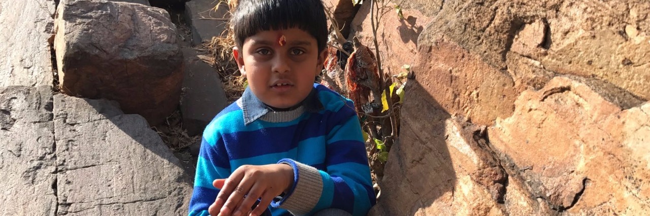 Lessons From a Trip to India With My Son on the Autism Spectrum young boy sitting amongst rocks
