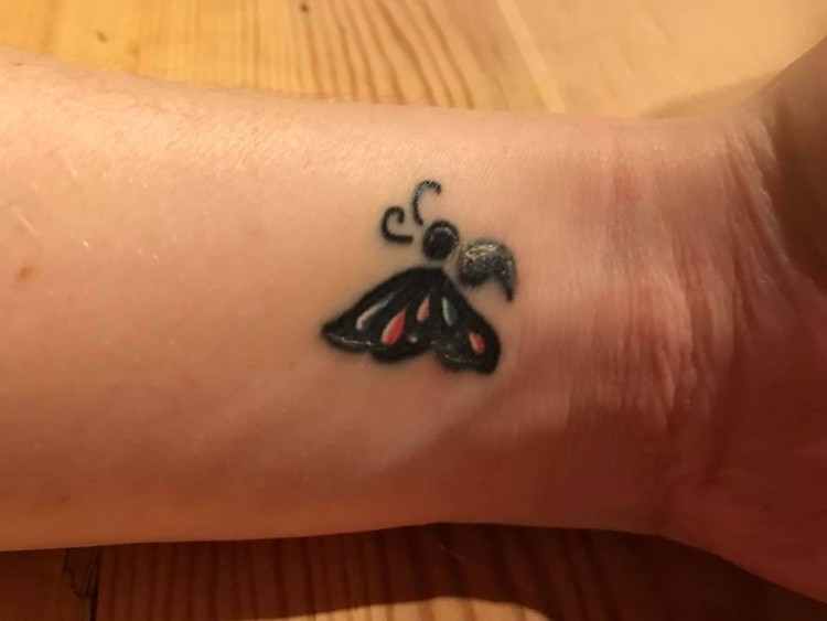 A butterfly tattoo with a semicolon as its body