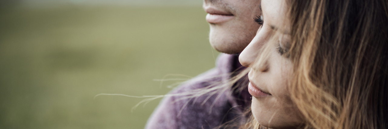 When You Share Your Bipolar Disorder With Your Significant Other Young loving couple outdoors sitting on grass, hugging and looking away, future and relationships concept