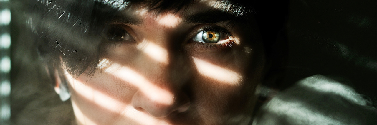 A closeup of a woman's face with smoke to the side and a shadow caste over her face