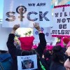 woman holding sign that says we are sick