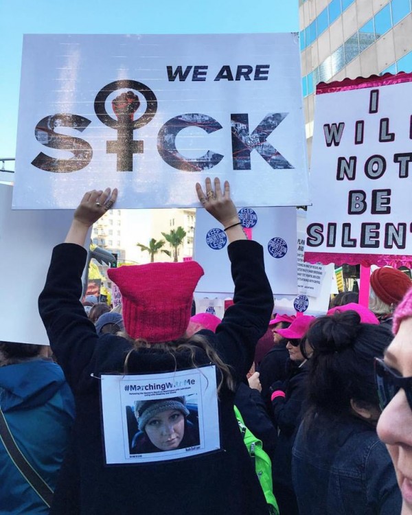 woman holding sign that says we are sick