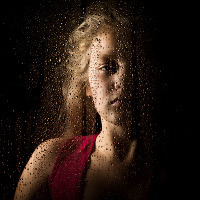 solemn young woman behind the window with drops.
