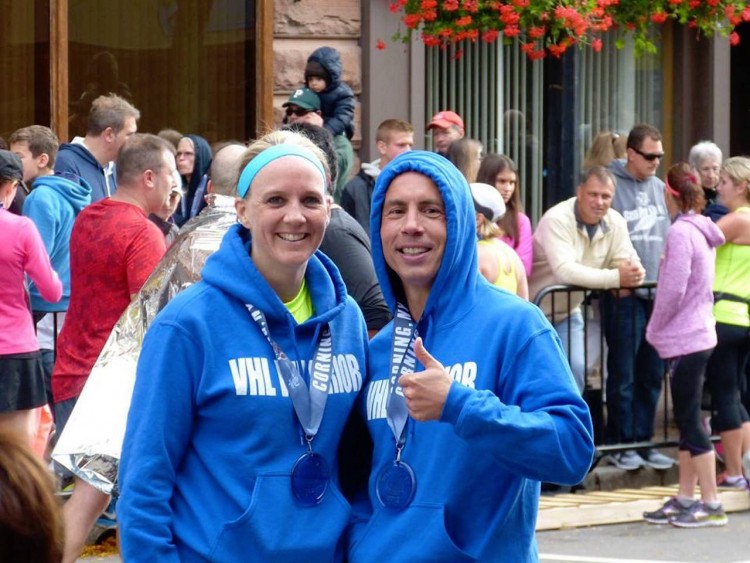 husband and wife wearing blue hoodies and medals after running a race
