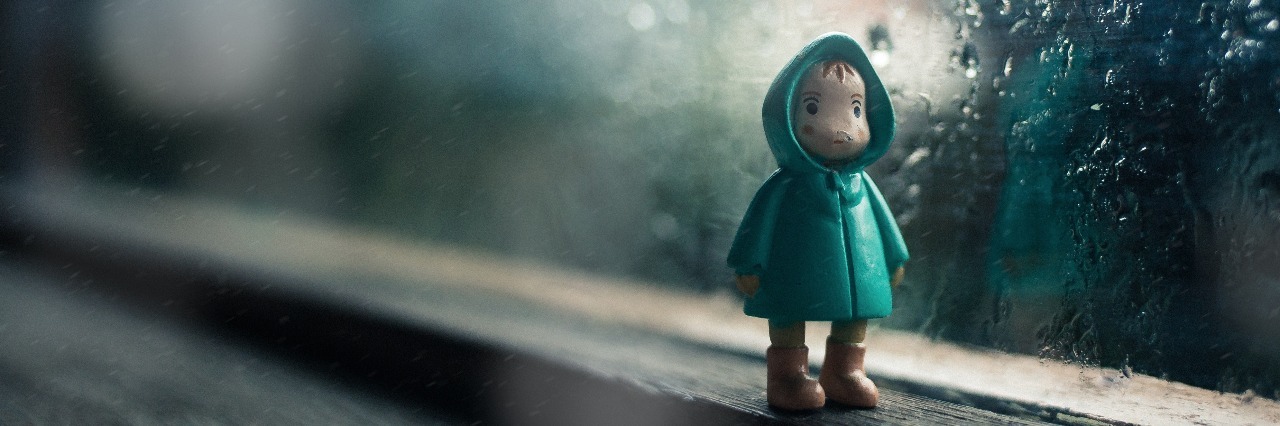 small figurine of man in a raincoat on a windowsill. it's raining outside