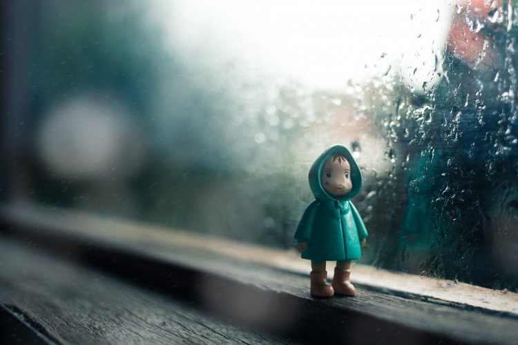 small figurine of man in a raincoat on a windowsill. it's raining outside