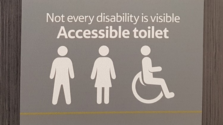 Image of a Tesco bathroom sign which says "not every disability is visible. Accessible toilet." and then shows the symbols for a man, woman and wheelchair sign.