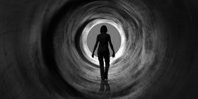 woman walking down a tunnel towards the light