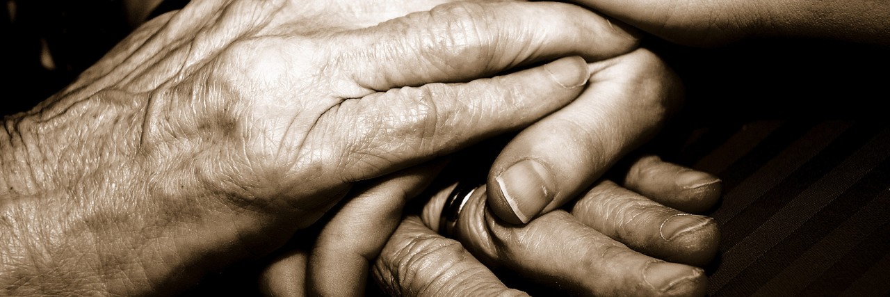 Close-up of a senior woman's hands holding her granddaughter's hands
