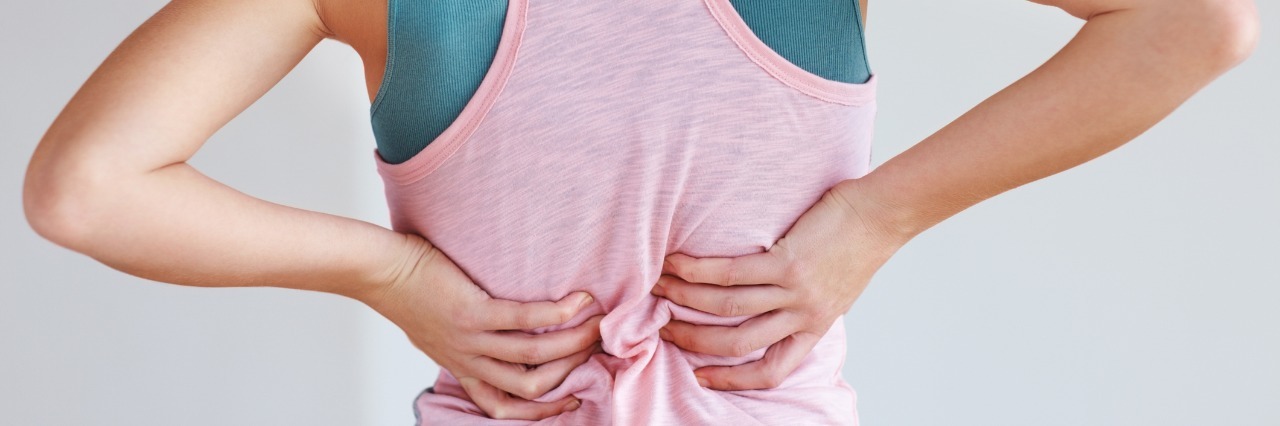 The Challenging Invisible Nature of Scimitar Syndrome woman in a pink tank top holding her back in pain