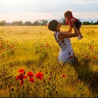 A woman holding up her child in a field of flowers