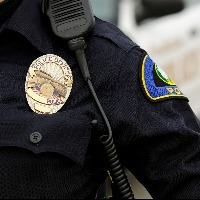 a close up of an officers uniform and badge with a patrol car in the background