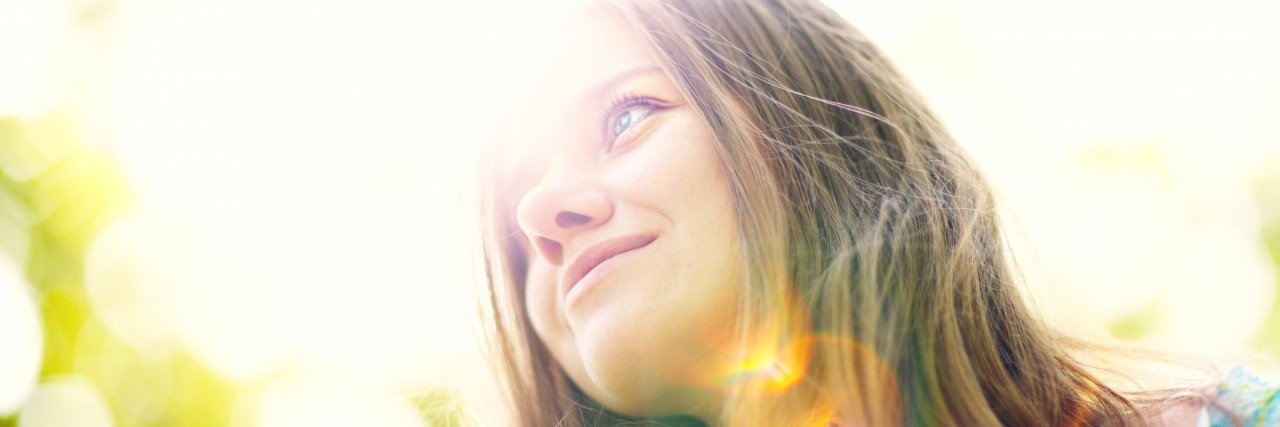 Young woman smiling in sunlight.