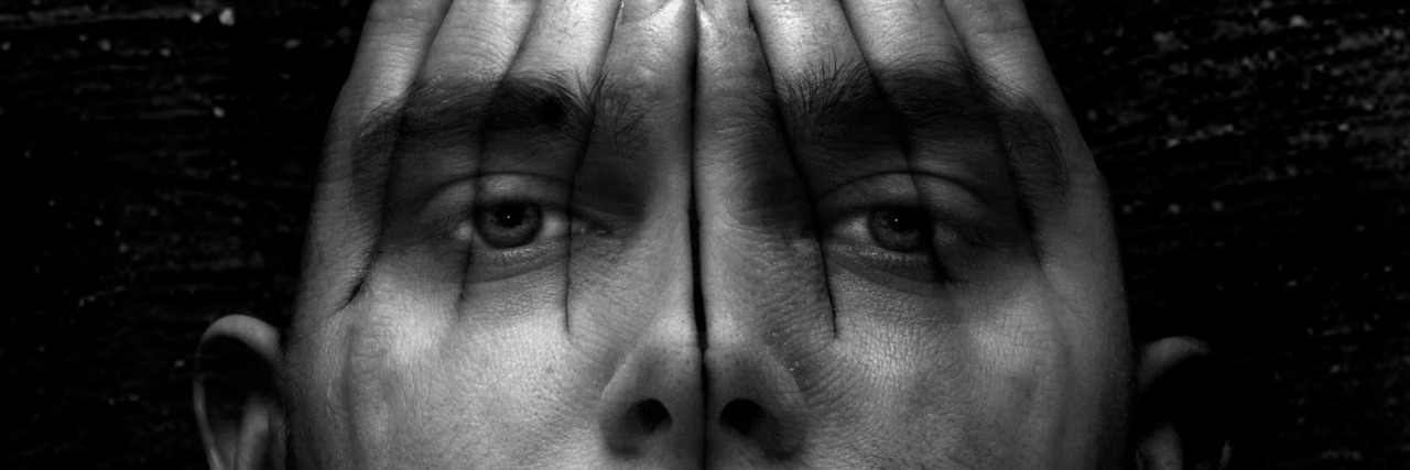 My Life With Anxiety: A Poem A concept artwork of a male face covered with see-through hands on a textured black background.