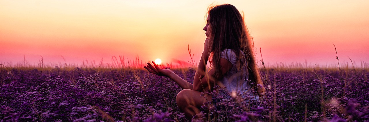 A woman standing in a field of flowers at sunset