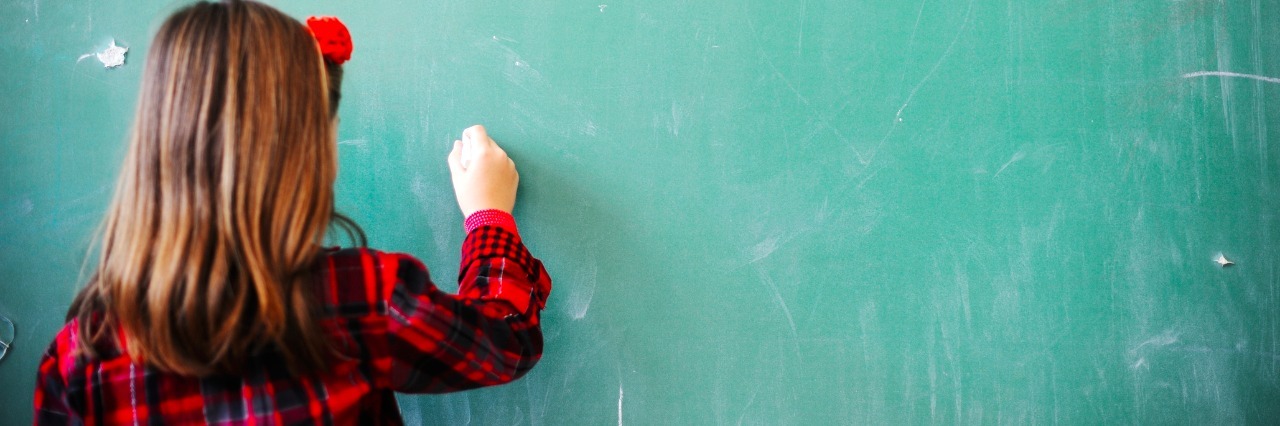 How I Helped My Daughter Go to School With Lyme Disease girl writing on a chalkboard